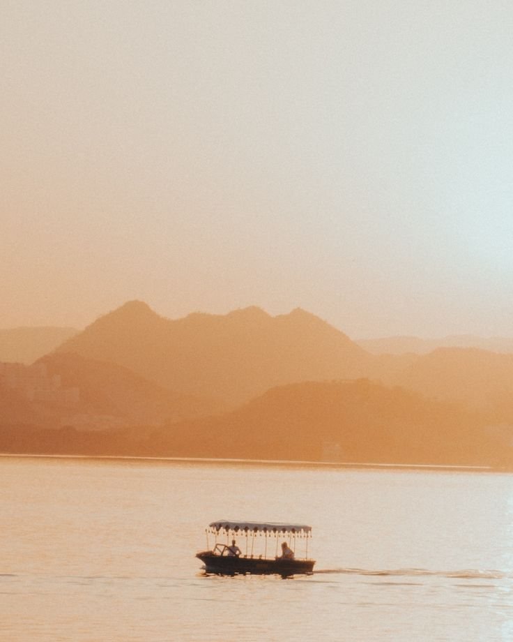 A canopied boat on Lake Pichola in golden haze